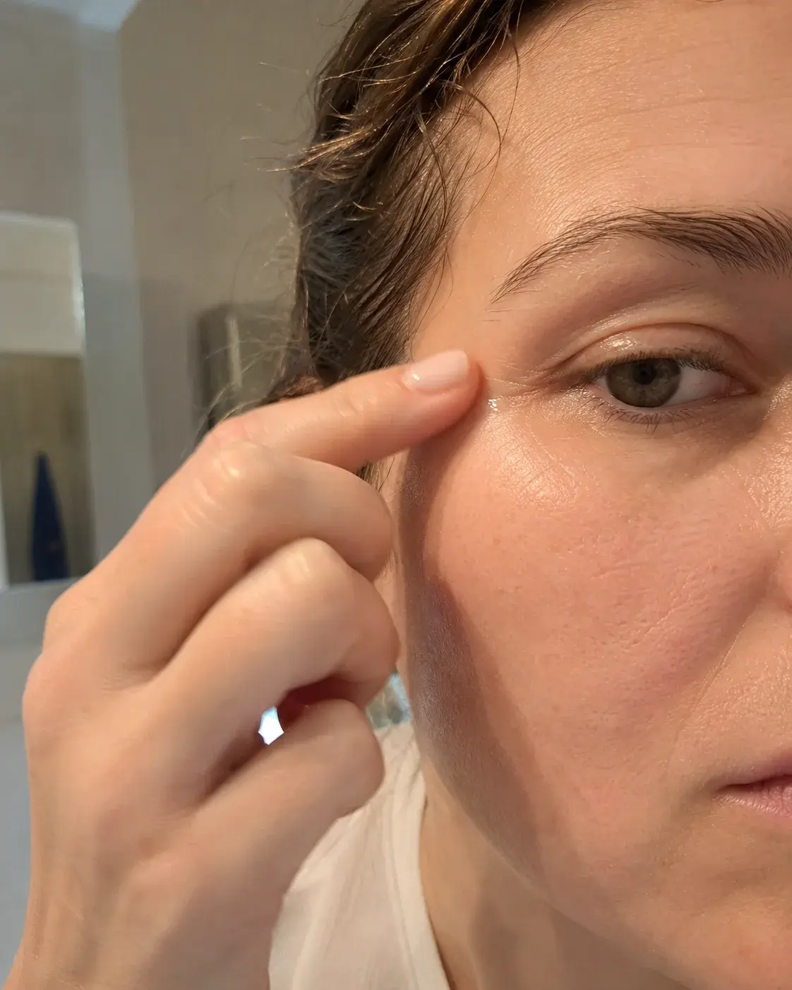 Žena nanosi ricinusovo ulje u predeo bora oko očiju