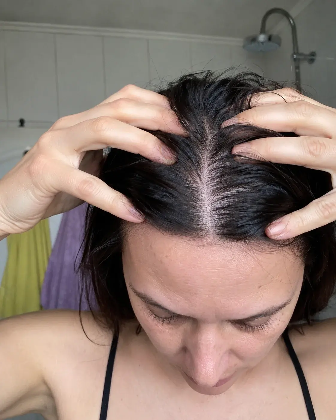 Žena masira skalp prstima u kupatilskom svetlu